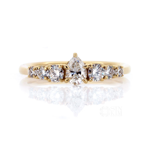 Pear  shape centre stone flanked by tapering sized round brilliant cut diamonds, set in 14k yellow gold.